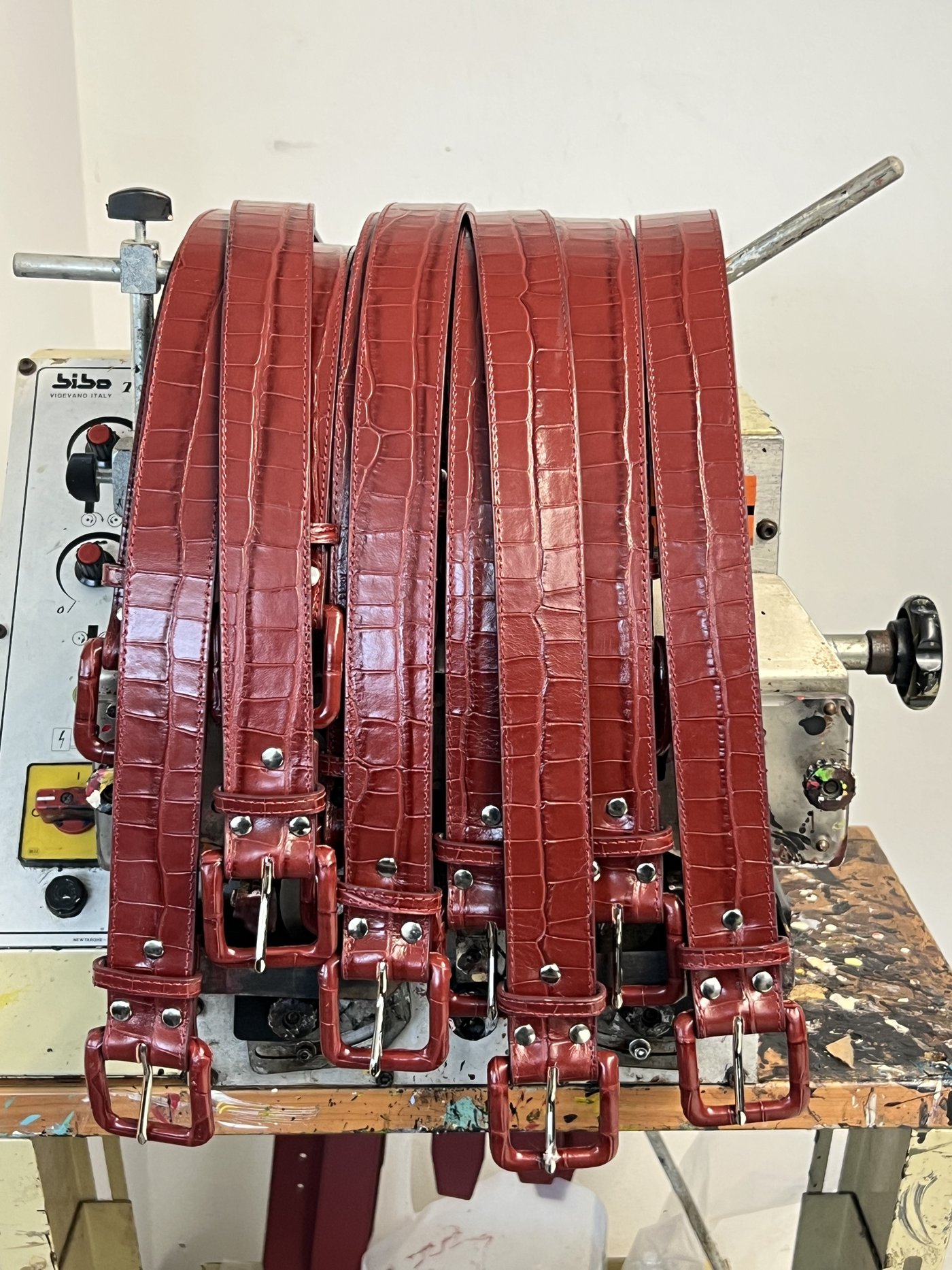 Line of Croc Tober deep red crocodile belts with wrapped buckles