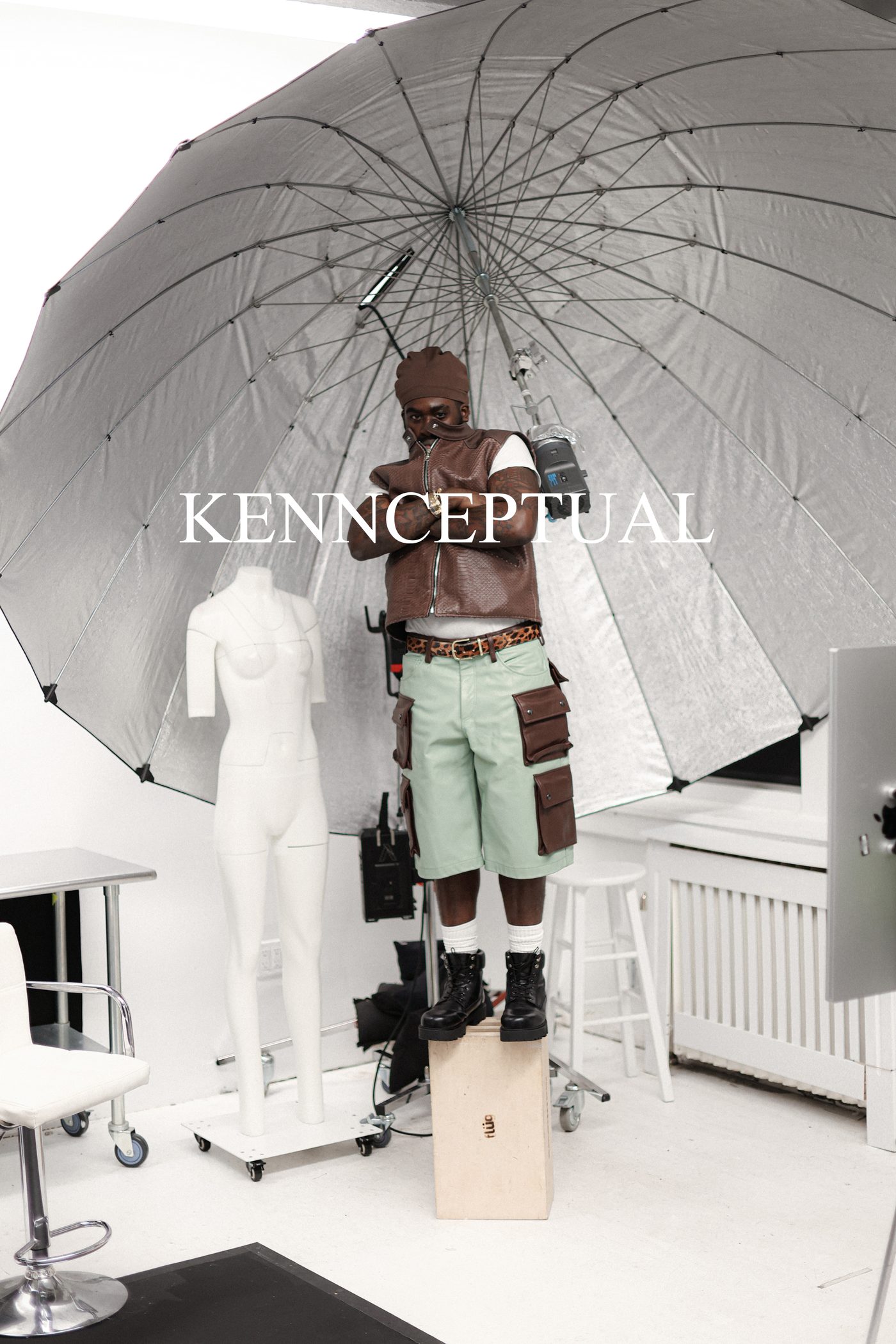 Behind the scenes, model wearing V2 Vest, cargo shorts and leopard belt under studio umbrella light