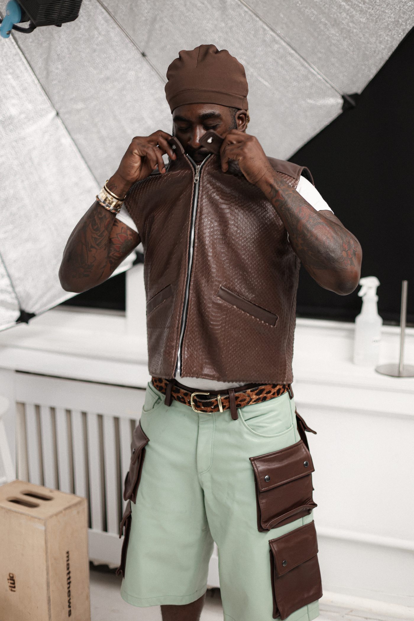 Behind the scenes, model zipping up V2 Vest over cargo shorts